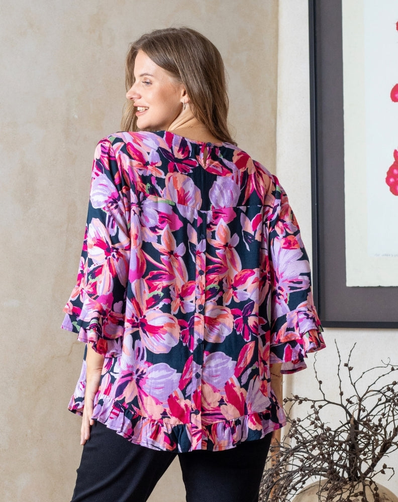 Woman wearing a colorful floral blouse indoors.
