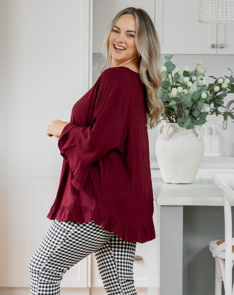 Woman wearing a burgundy top and checkered pants in a kitchen setting