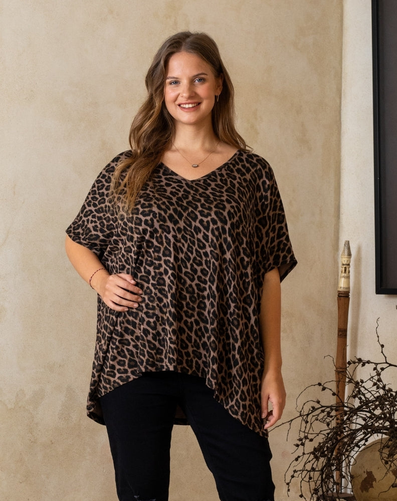 Woman wearing a leopard print top against a beige wall.