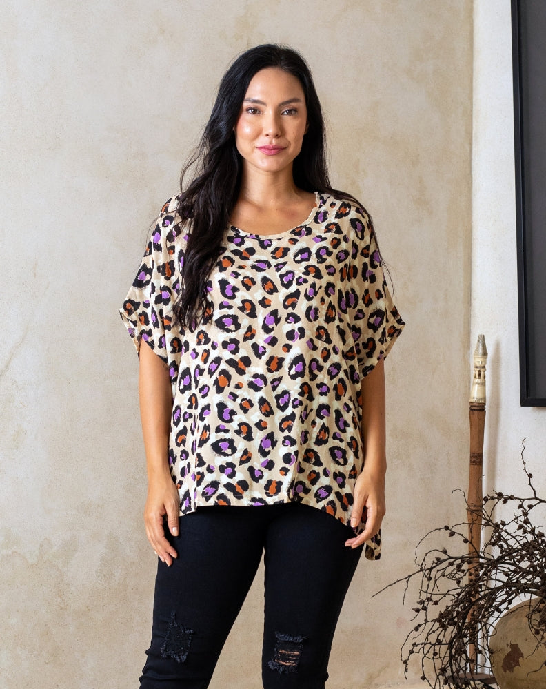 Woman wearing a leopard print top against a neutral wall.