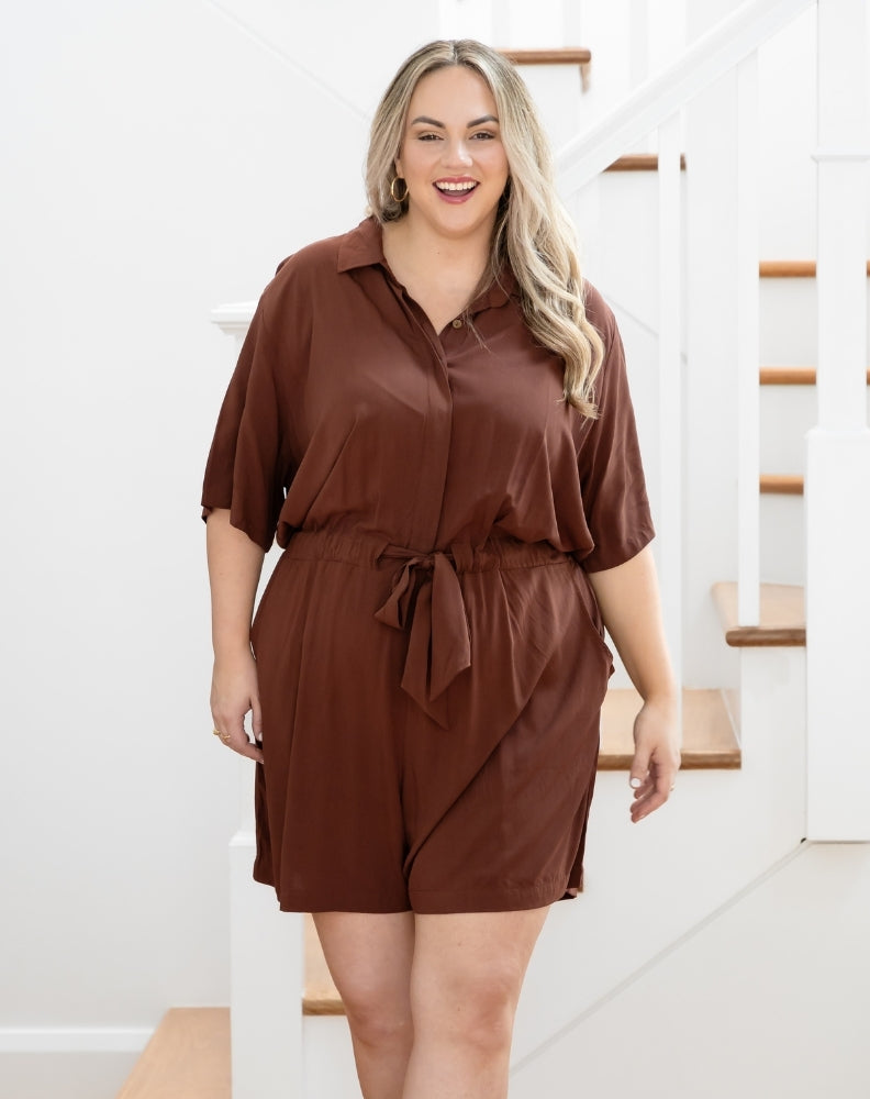 Woman wearing a brown dress standing in a home setting.