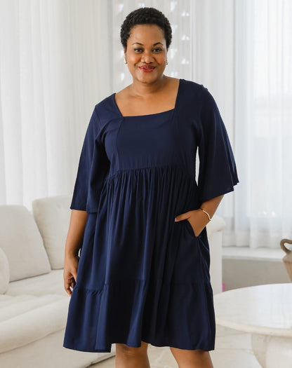 Woman wearing a navy blue dress in a living room setting