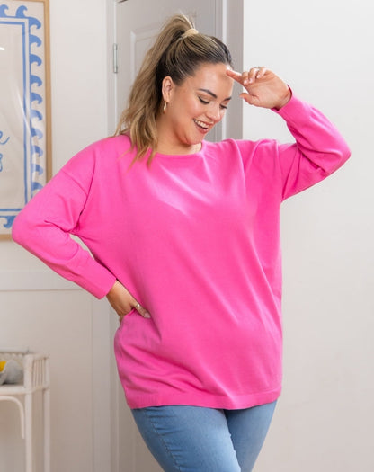 Person wearing a bright pink sweatshirt and blue jeans indoors.