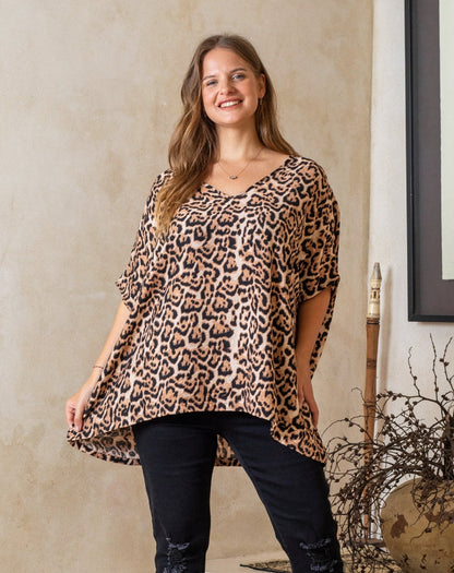 Woman wearing a leopard print top and black pants indoors.