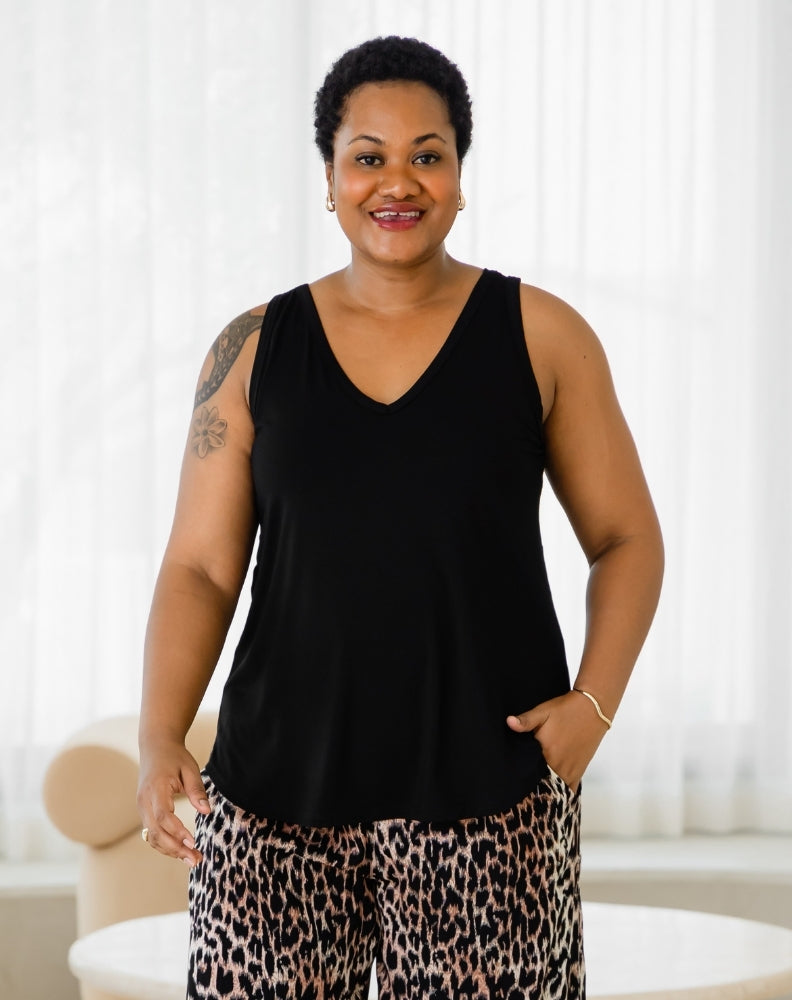 Woman wearing a black sleeveless top and leopard print pants indoors.