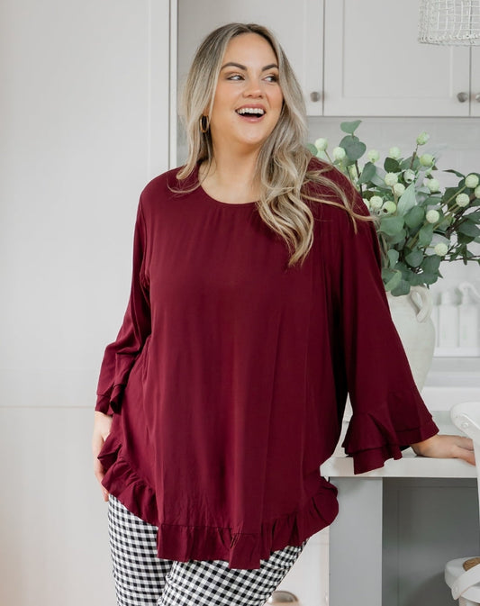 Woman wearing a burgundy top and checkered pants in a kitchen setting