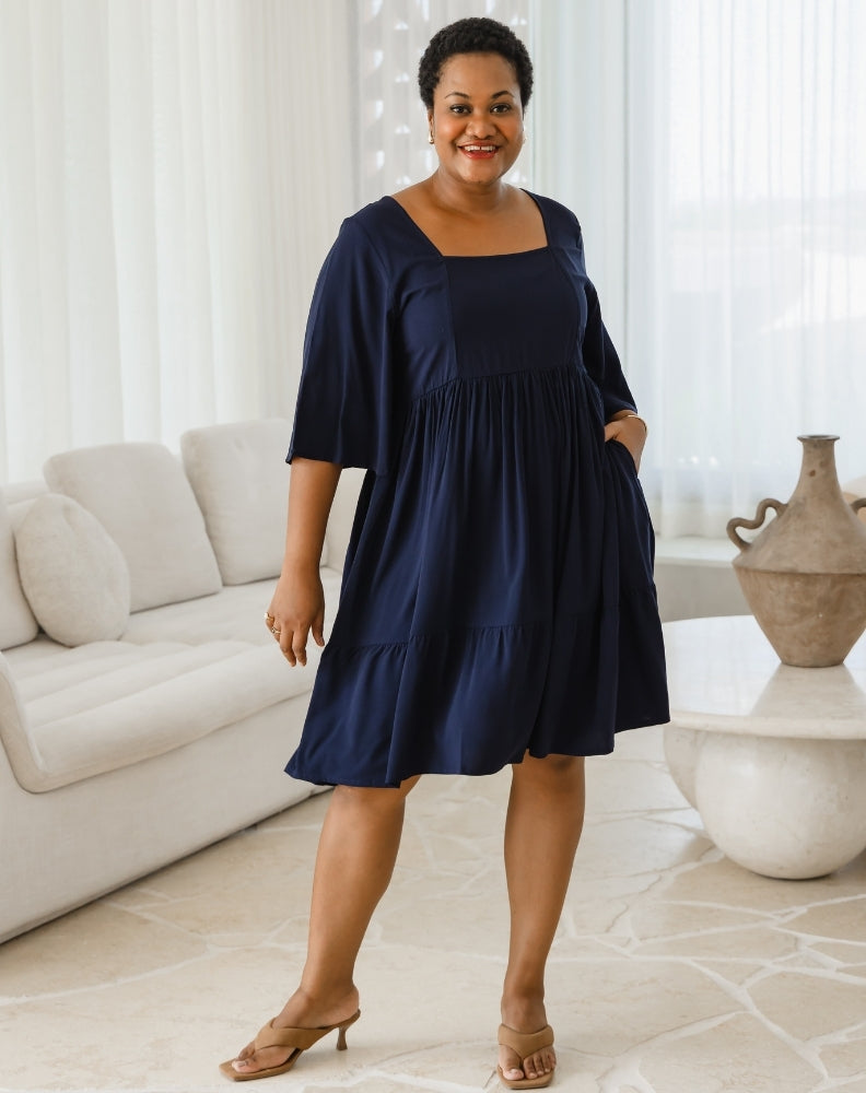 Woman wearing a navy blue dress in a living room setting