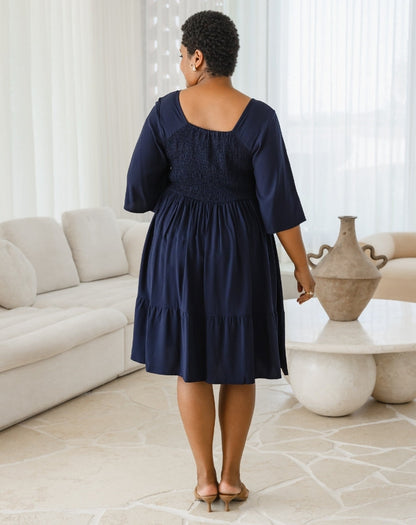 Woman wearing a navy blue dress in a living room setting