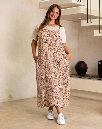 Woman wearing a long, patterned apron over a white shirt in a kitchen setting.