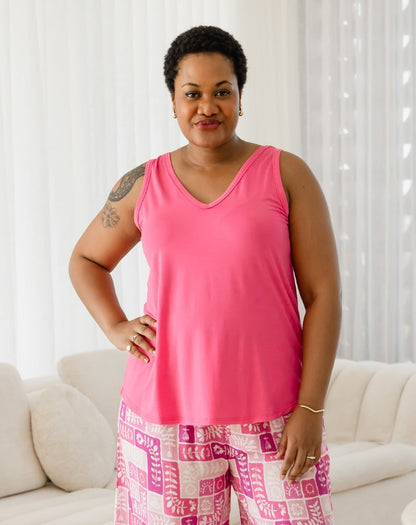 Woman wearing a pink tank top and patterned shorts standing in a living room.