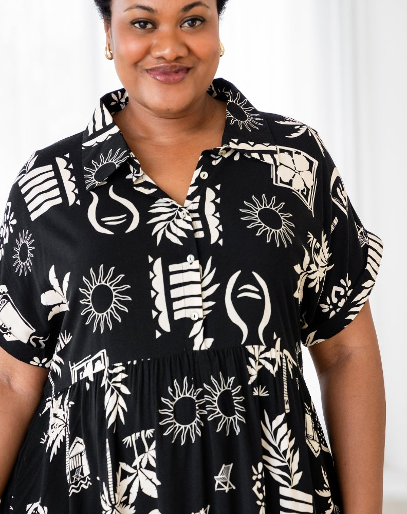 Woman wearing a black dress with white geometric patterns against a white background