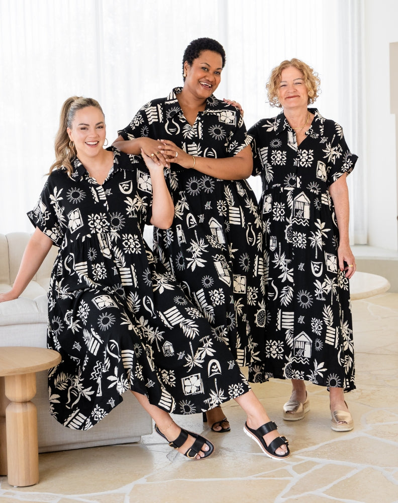Three women wearing black and white patterned dresses in a living room setting.