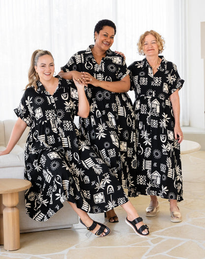 Three women wearing black and white patterned dresses in a living room setting.