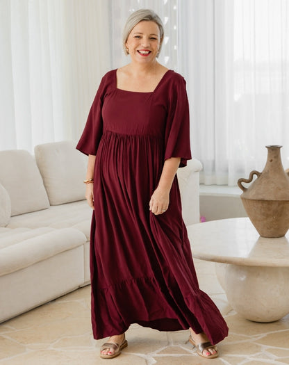 Woman wearing a burgundy dress in a living room setting