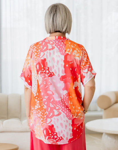 Person wearing a colorful kimono-style garment in a room with white walls and furniture.