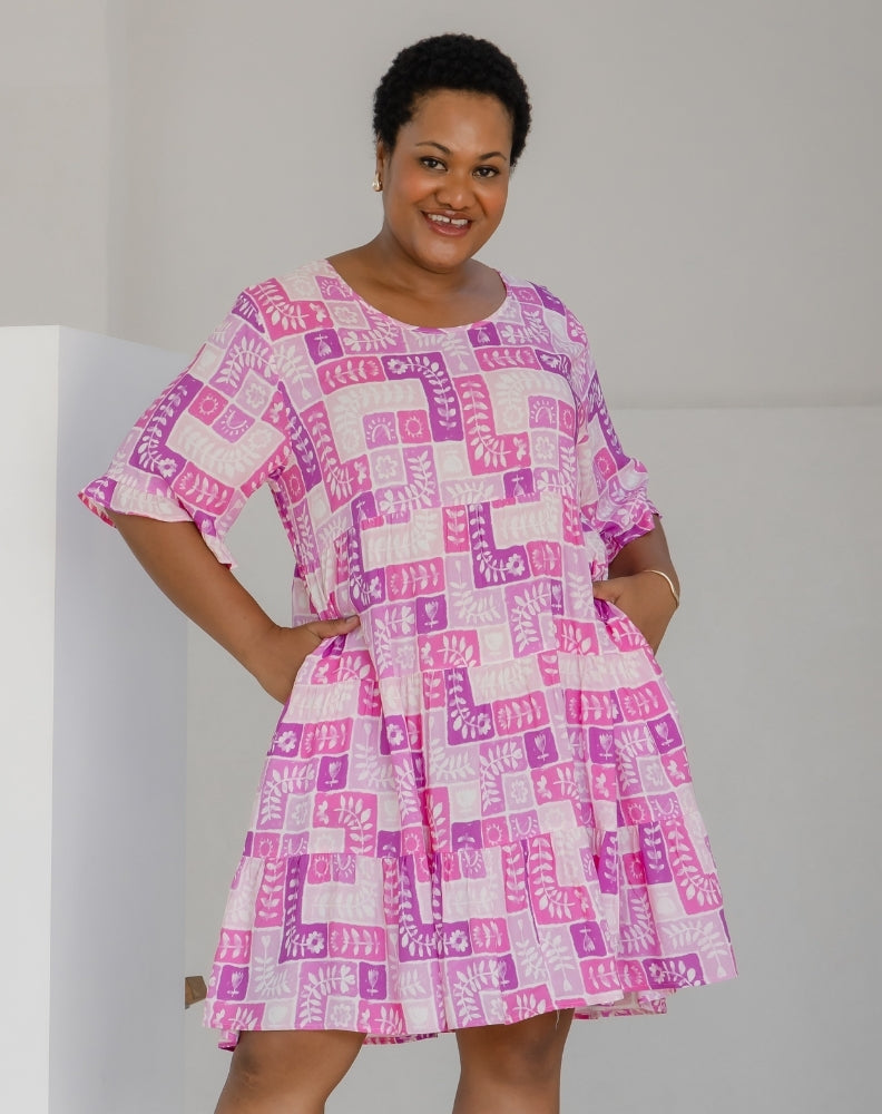 Woman wearing a pink and white patterned dress against a plain background