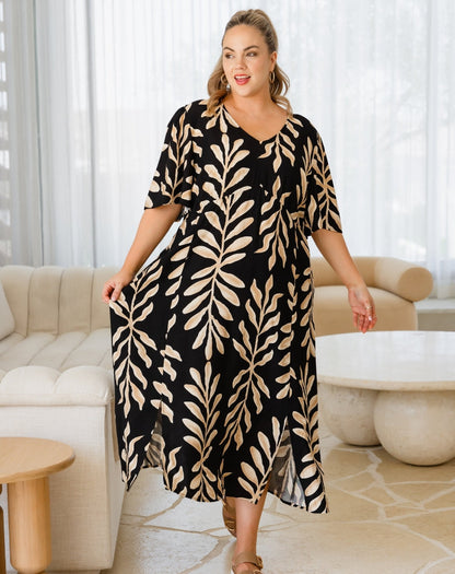 Woman wearing a black and beige leaf patterned dress in a living room.