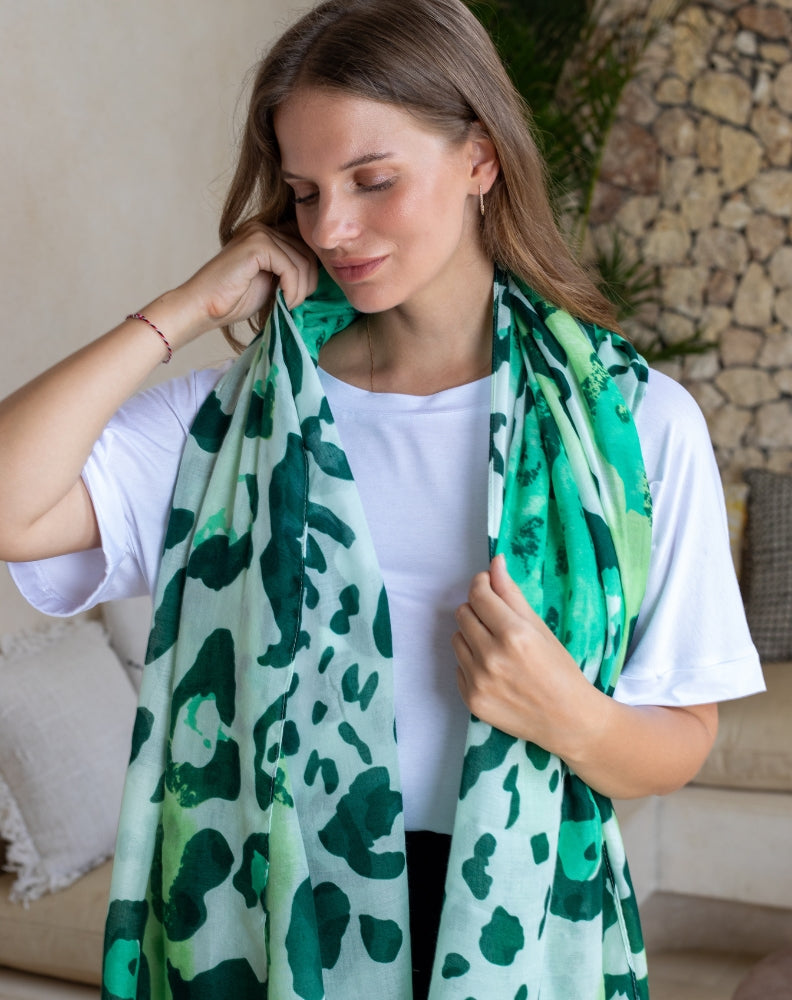 Woman wearing a green and white patterned scarf in a casual setting.
