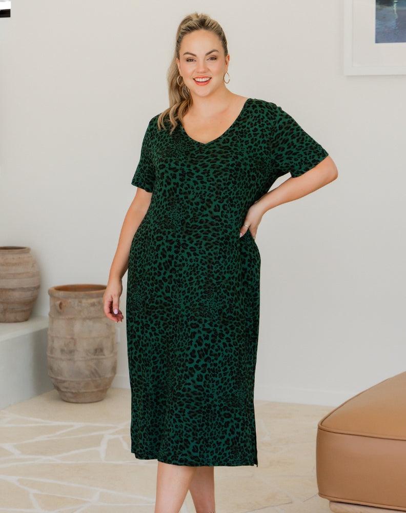 Woman wearing a green dress with a leopard print pattern indoors.