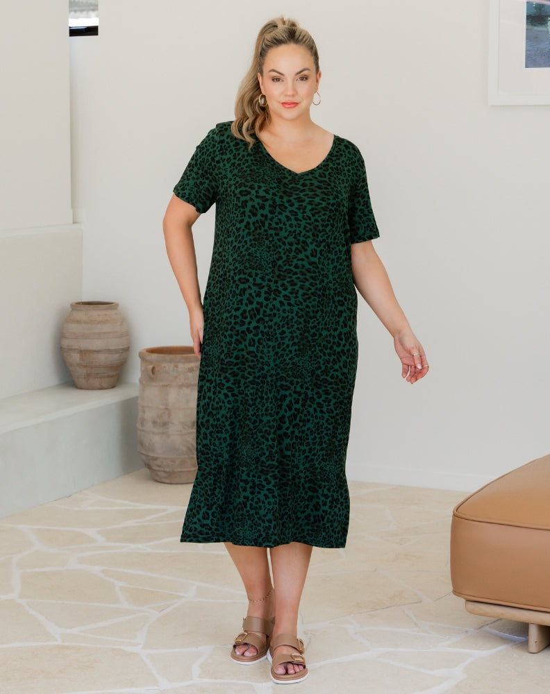 Woman wearing a green dress with a pattern in an indoor setting
