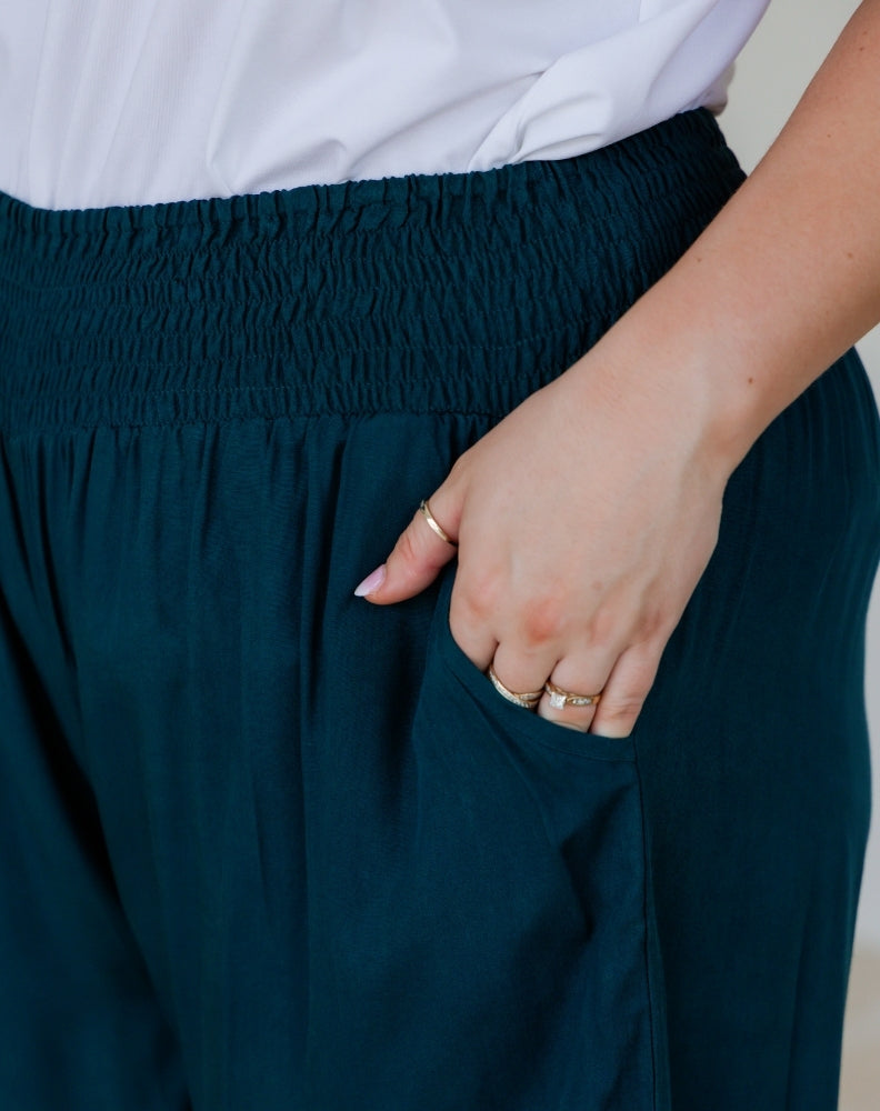 Person wearing a navy skirt with a white top, holding the waistband.