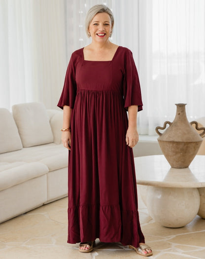 Woman wearing a burgundy dress in a living room setting