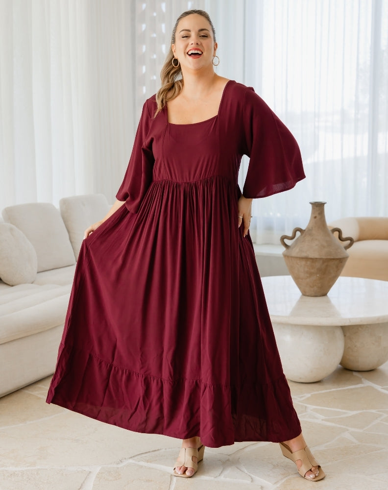 Woman wearing a burgundy dress in a living room setting