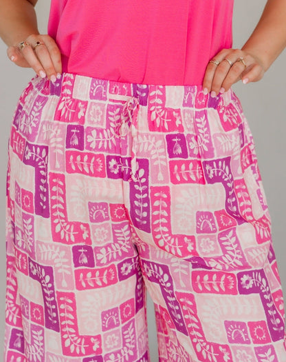 Person wearing pink and white patterned pants with a pink top against a gray background