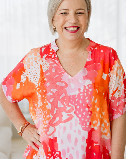 Woman wearing a colorful patterned blouse with a blurred background